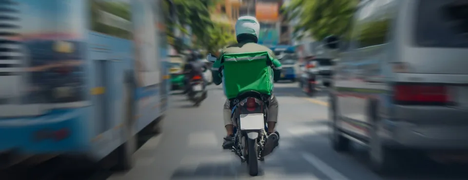 Delivery rider travelling through a city on a scooter